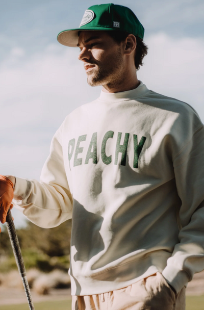 A man wearing a Devereux Golf grey 'Peachy' sweater and green hat