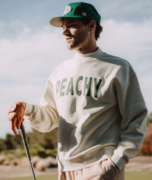 A man wearing a Devereux Golf grey 'Peachy' sweater and green hat