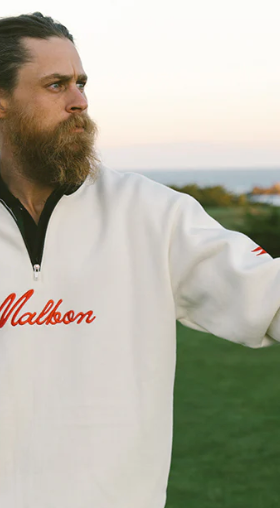 A man wearing a white Malbon golf sweater and golf glove