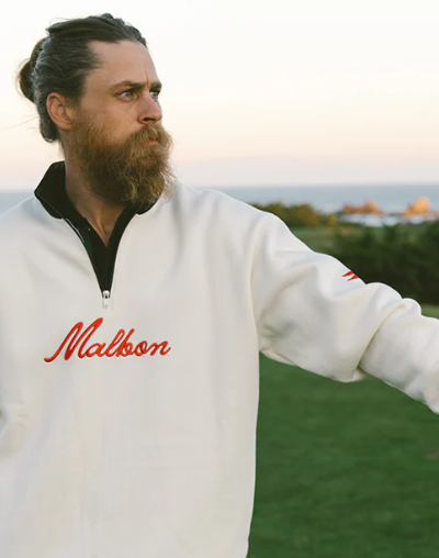 A man wearing a white Malbon golf sweater and golf glove