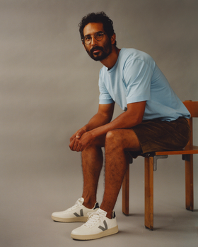 A man wearing a light blue Veja t-shirt with shorts and Veja logo white shoes
