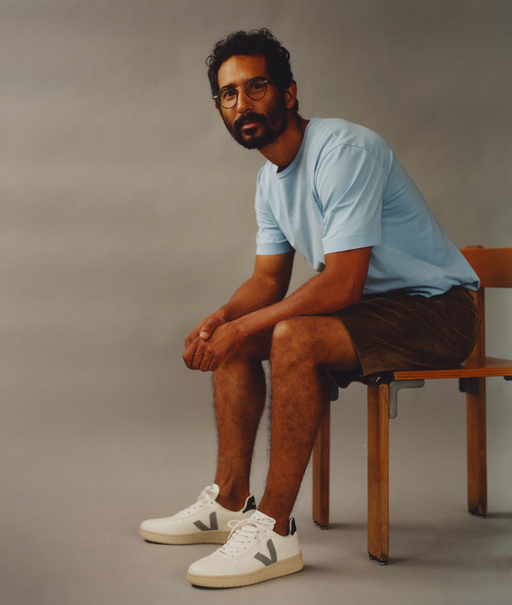 A man wearing a light blue Veja t-shirt with shorts and Veja logo white shoes