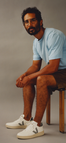 A man wearing a light blue Veja t-shirt with shorts and Veja logo white shoes