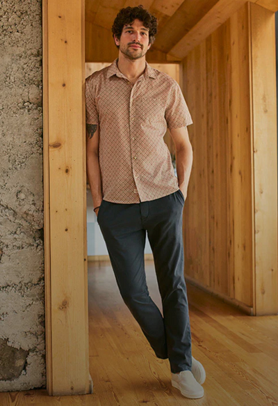 A man wearing a short-sleeve Marine Layer and navy blue pants