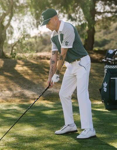 A man wearing a green Bogey Boys golf outfit in collaboration with Adidas