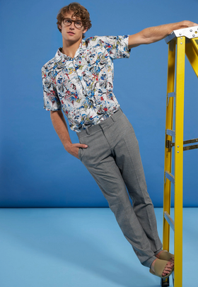 A man wearing a floral Perry Ellis button up and grey slacks