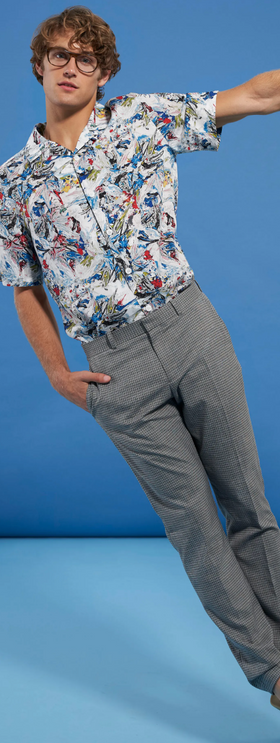 A man wearing a floral Perry Ellis button up and grey slacks