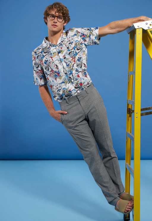 A man wearing a floral Perry Ellis button up and grey slacks