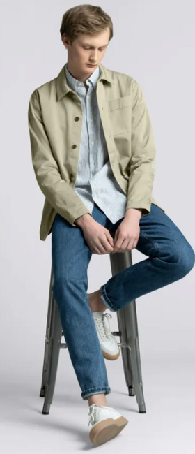 A man wearing an Asket green jacket and blue pants