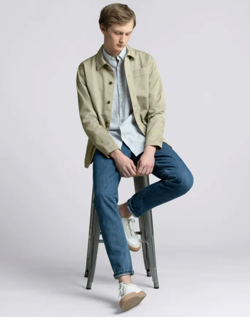 A man wearing an Asket green jacket and blue pants