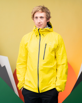 A man wearing a bright yellow Haglöfs jacket and black pants