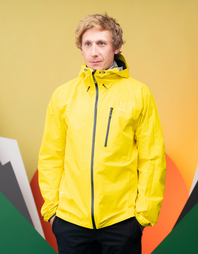 A man wearing a bright yellow Haglöfs jacket and black pants