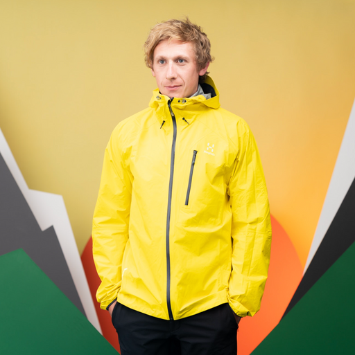 A man wearing a bright yellow Haglöfs jacket and black pants