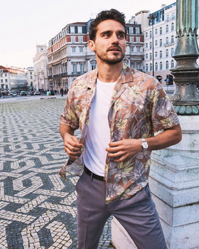 A man wearing a floral Bonobos button-up with a white t-shirt and grey slacks