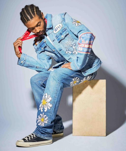 A man wearing a True Religion jean jacket and matching pants with flowers embroidered on it