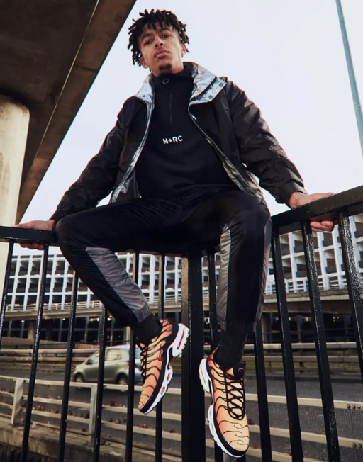 A man wearing a m+rc noir baclk fleece, jacket and track pants