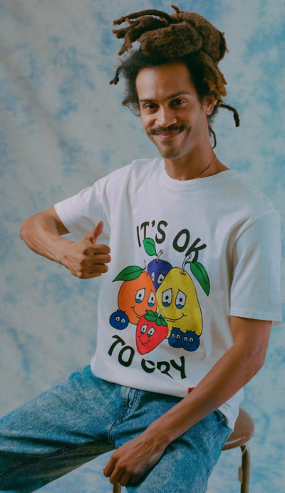 A man wearing a It's okay to Cry' chnge white t-shirt with fruits on it