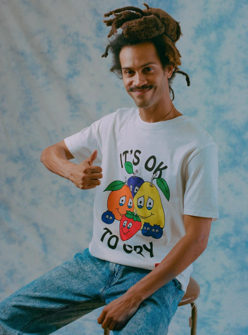 A man wearing a It's okay to Cry' chnge white t-shirt with fruits on it