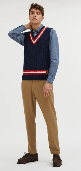 A man wearing a preppy vest from Baracuta and brown slacks