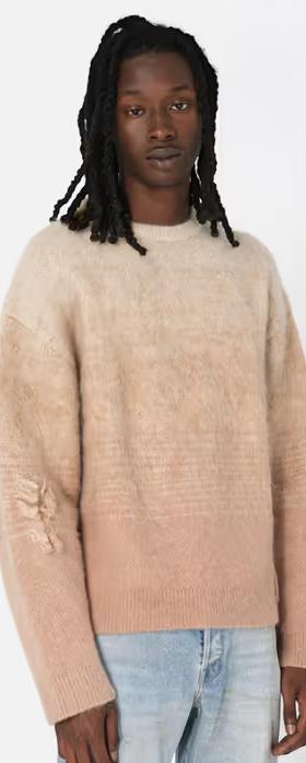 A man wearing a beige gradient sweater and light blue jeans