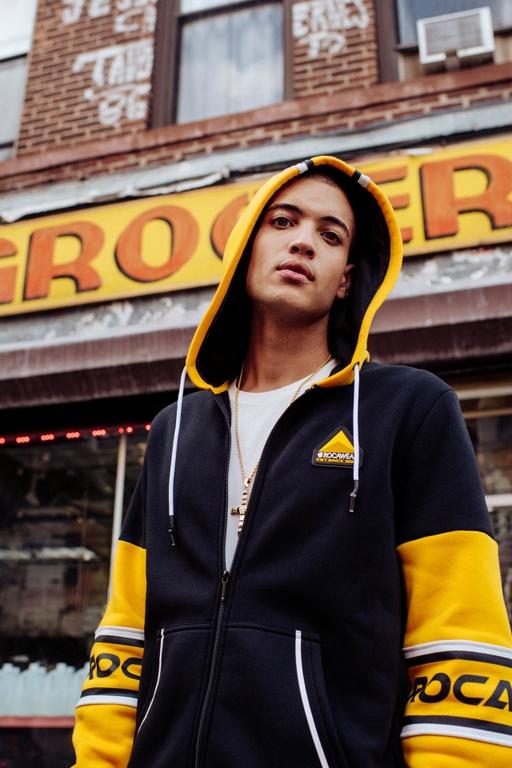 A man wearing a Rocawear yellow and black zip-up hoodie