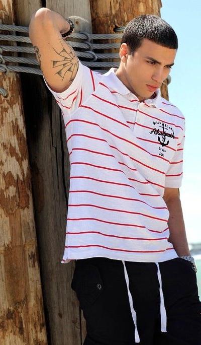 A man wearing a striped red and white Akademiks polo shirt