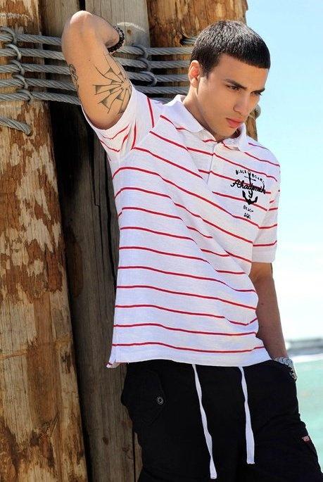 A man wearing a striped red and white Akademiks polo shirt