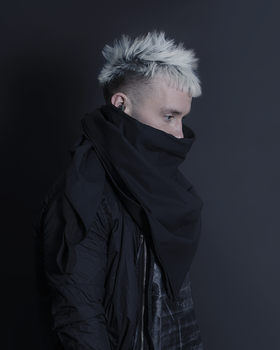 A man wearing a oversize AOKU black scarf and jacket