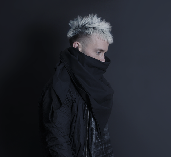 A man wearing a oversize AOKU black scarf and jacket