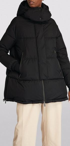 A man wearing a HERNO LAMINAR black long puffy jacket with beige pants