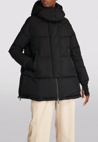 A man wearing a HERNO LAMINAR black long puffy jacket with beige pants