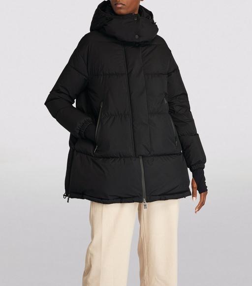A man wearing a HERNO LAMINAR black long puffy jacket with beige pants