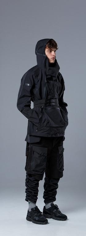 A man wearing a RIOT DIVISION black outfit featuring a technical jacket and pants