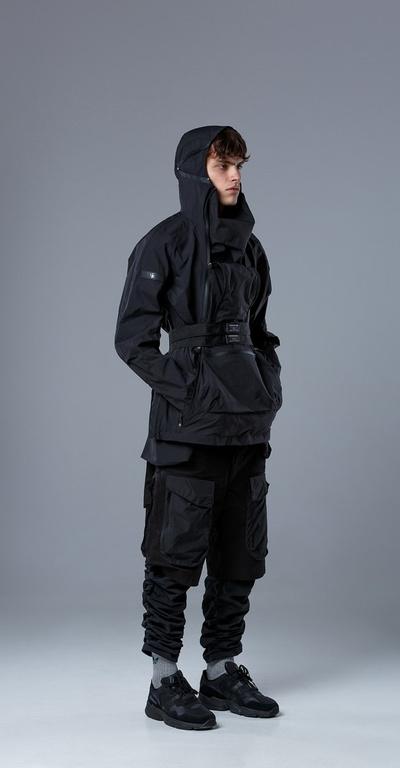 A man wearing a RIOT DIVISION black outfit featuring a technical jacket and pants