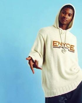 A man wearing an ENCYE cream branded hoodie with a large chain