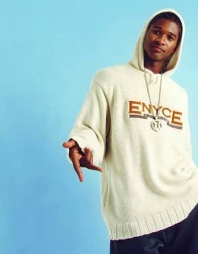 A man wearing an ENCYE cream branded hoodie with a large chain