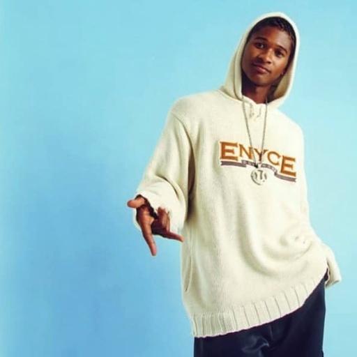 A man wearing an ENCYE cream branded hoodie with a large chain