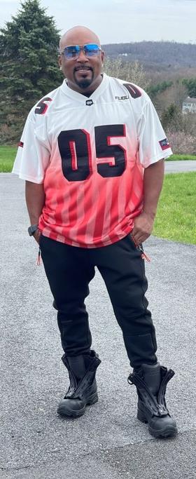 A man wearing a FUBU 05 red and white jersey with black pants