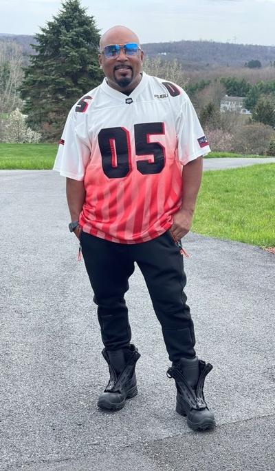 A man wearing a FUBU 05 red and white jersey with black pants