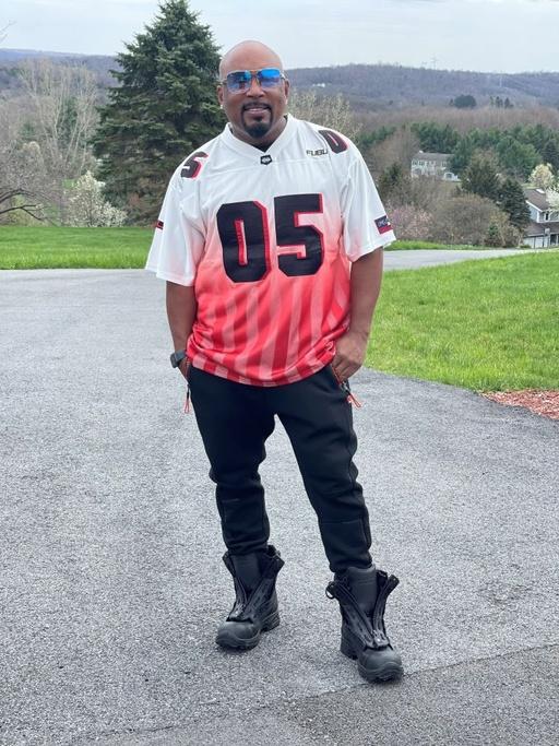 A man wearing a FUBU 05 red and white jersey with black pants