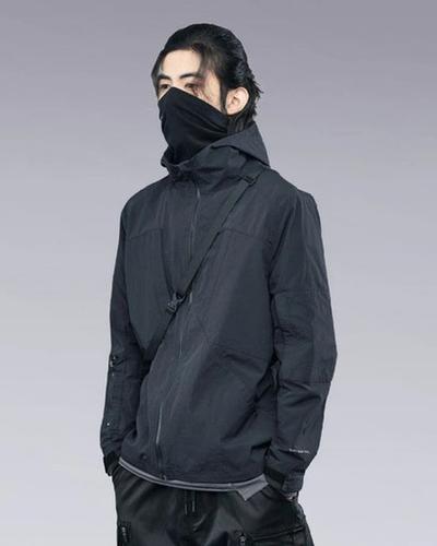 A man wearing a clotechnow black outfit featuring a black mask and technical jacket
