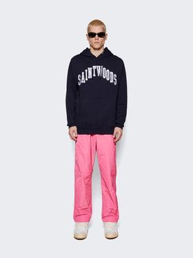 A man wearing a saintwoods branded navy hoodie with pink pants and sunglasses