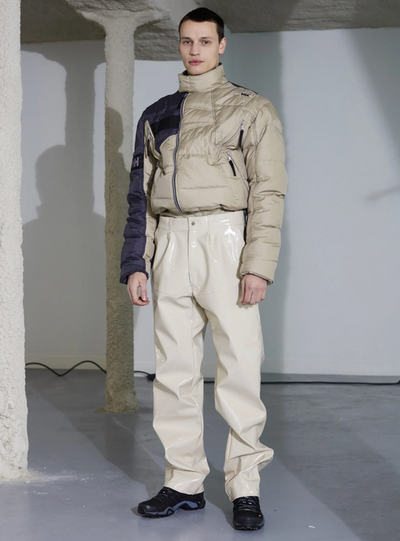 A man wearing a futuristic gmbh outfit featuring a puffy jacket and beige technical pnts