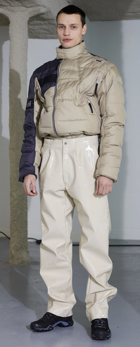 A man wearing a futuristic gmbh outfit featuring a puffy jacket and beige technical pnts