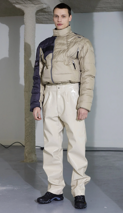 A man wearing a futuristic gmbh outfit featuring a puffy jacket and beige technical pnts