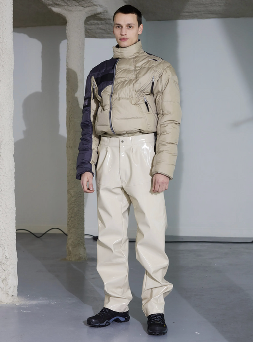 A man wearing a futuristic gmbh outfit featuring a puffy jacket and beige technical pnts