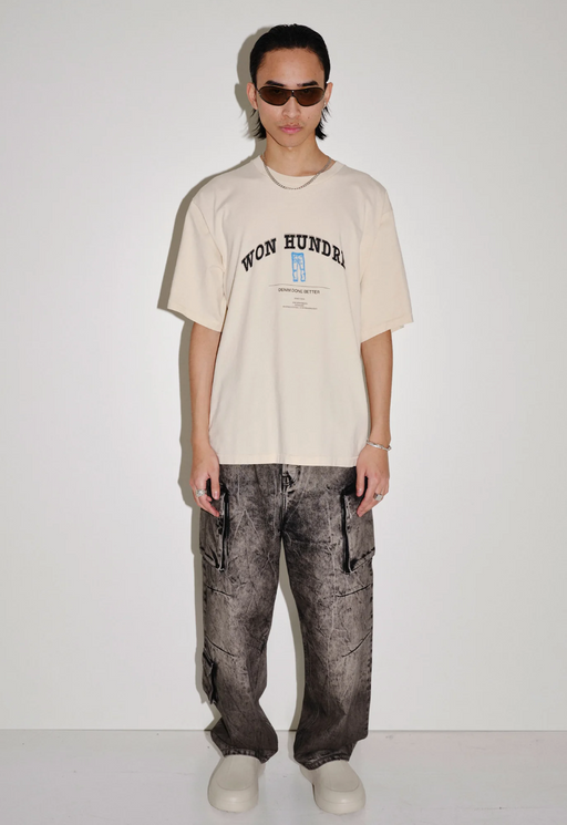 A man wearing a won hundred beige branded t-shirt and oversize black jeans
