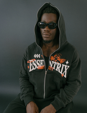 A man wearing an Essentrix branded zip up hoodie with sunglasses