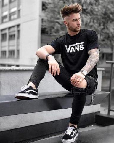 A man wearing a black vans t-shirt with black vans shoes with the classic white stripe