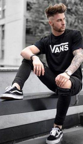 A man wearing a black vans t-shirt with black vans shoes with the classic white stripe